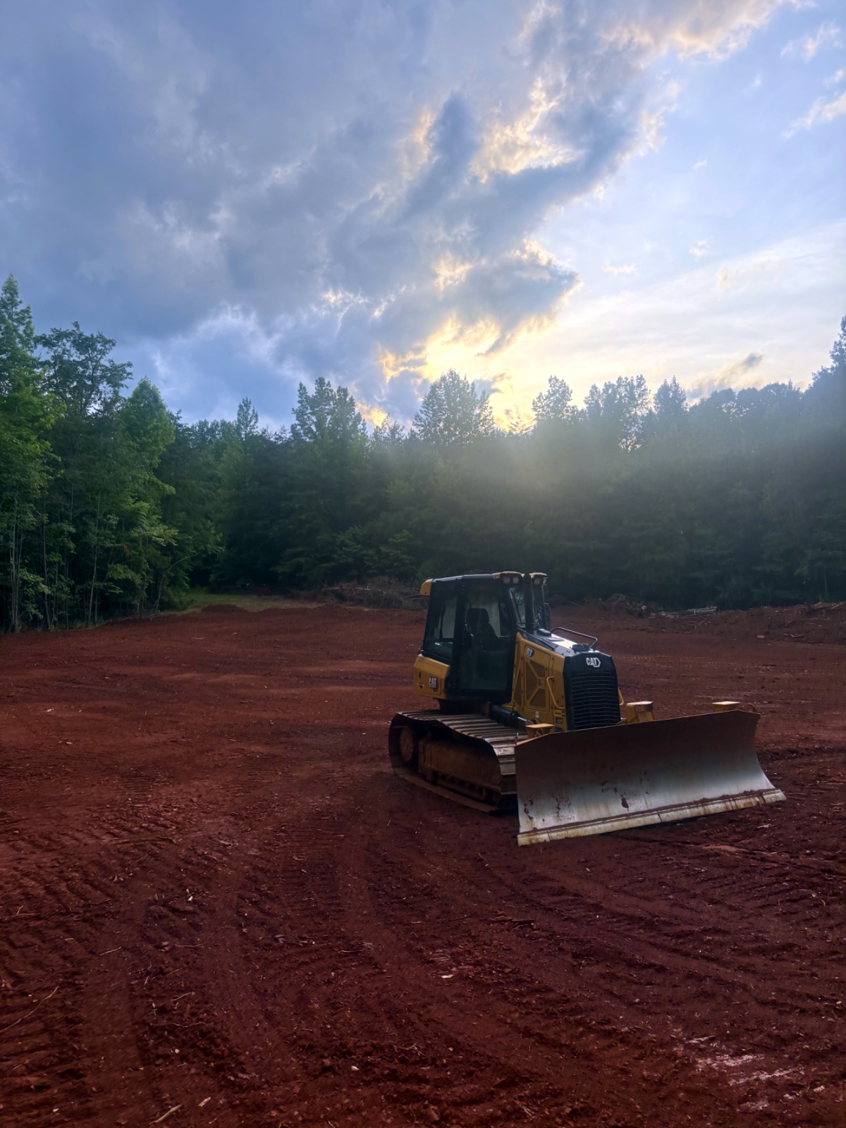 CAT dozer on a freshly graded red-clay site at sunset in Western North Carolina