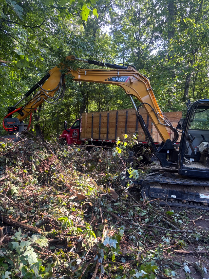 SANY excavator loading brush onto a flatbed truck in WNC