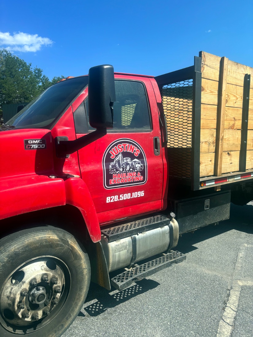 Justin's Hauling branded GMC flatbed loaded with lumber in Asheville, NC